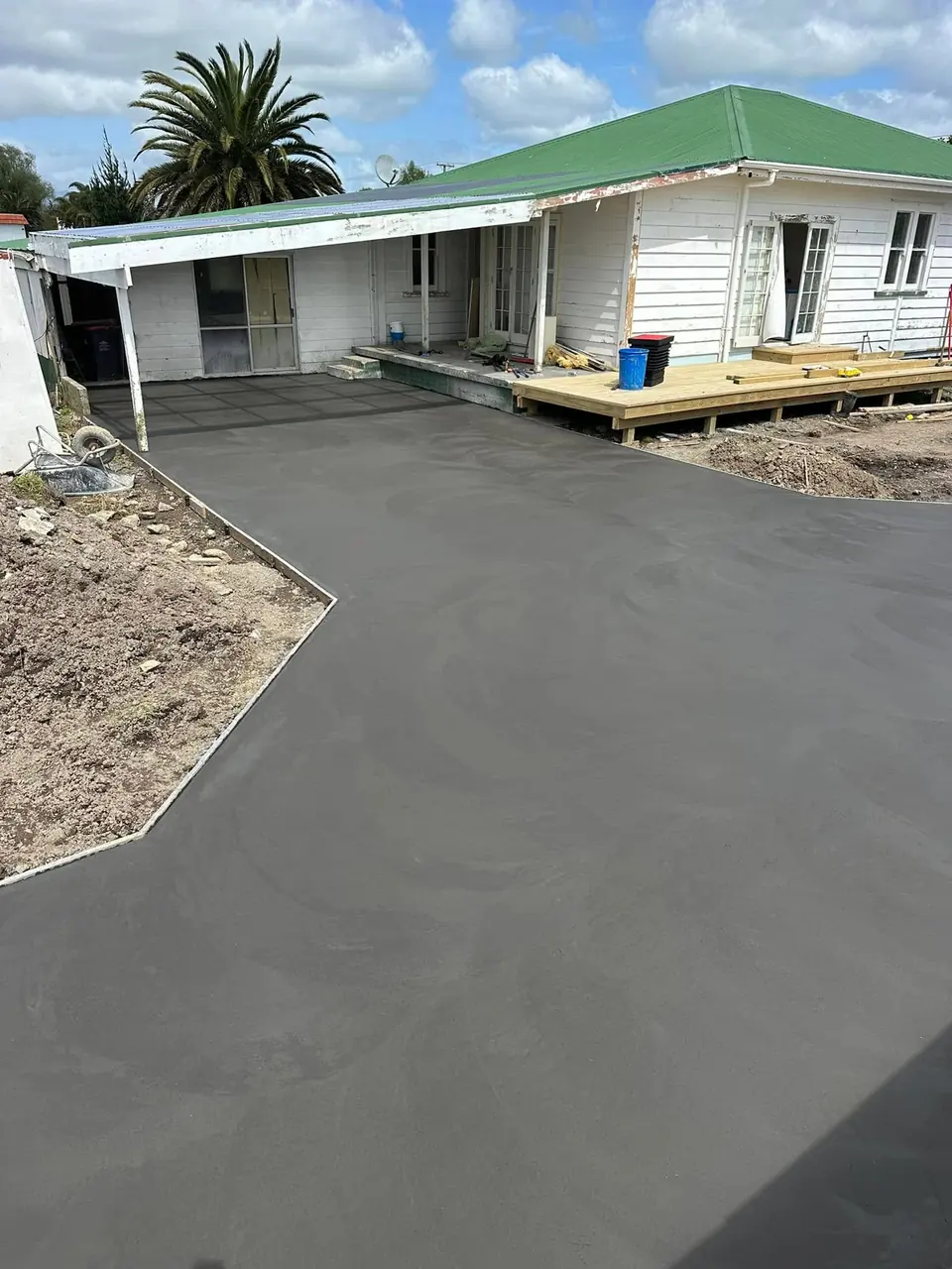 New concrete driveway running up to a carport beside an older home